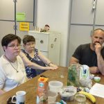 Három résztvevő figyelmesen hallgatja a klubvezető előadását