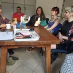 Az asztal körül ül a rehabklub pár résztvevője, az előadókkal beszélgetnek