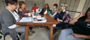 Az asztal körül ül a rehabklub pár résztvevője, az előadókkal beszélgetnek