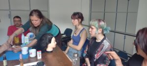 Egy résztvevő egy krémet mutat pár másik jelenlévőnek